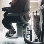 Woman using stairlift to ascend stairs.