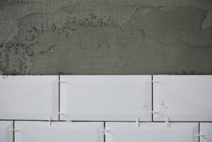 White tiles laid on the grey concrete. Maintenance repair works renovation in the flat. Restoration indoors. Work in process.