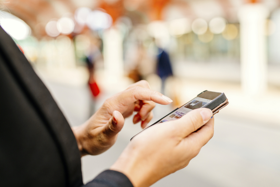 Midsection of businesswoman using smart phone at railroad station
