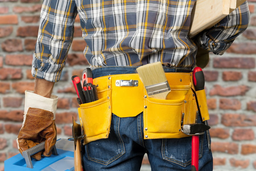 Tradesman with Tools and Lumber in Front of Wall
