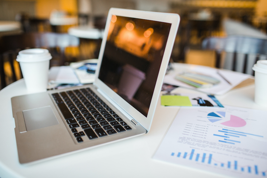 Open laptop, financial document and other objects on workplace of business people
